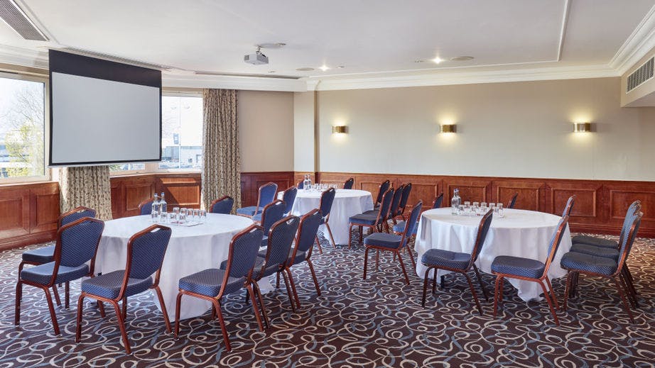 Meeting room with round tables and large screen for corporate events in Southampton.