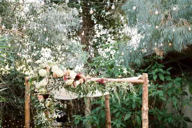 Outdoor courtyard with rustic arch and floral decor, perfect for weddings and gatherings.