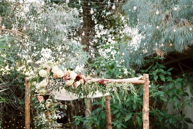 Outdoor courtyard with rustic arch and floral decor, perfect for weddings and gatherings.