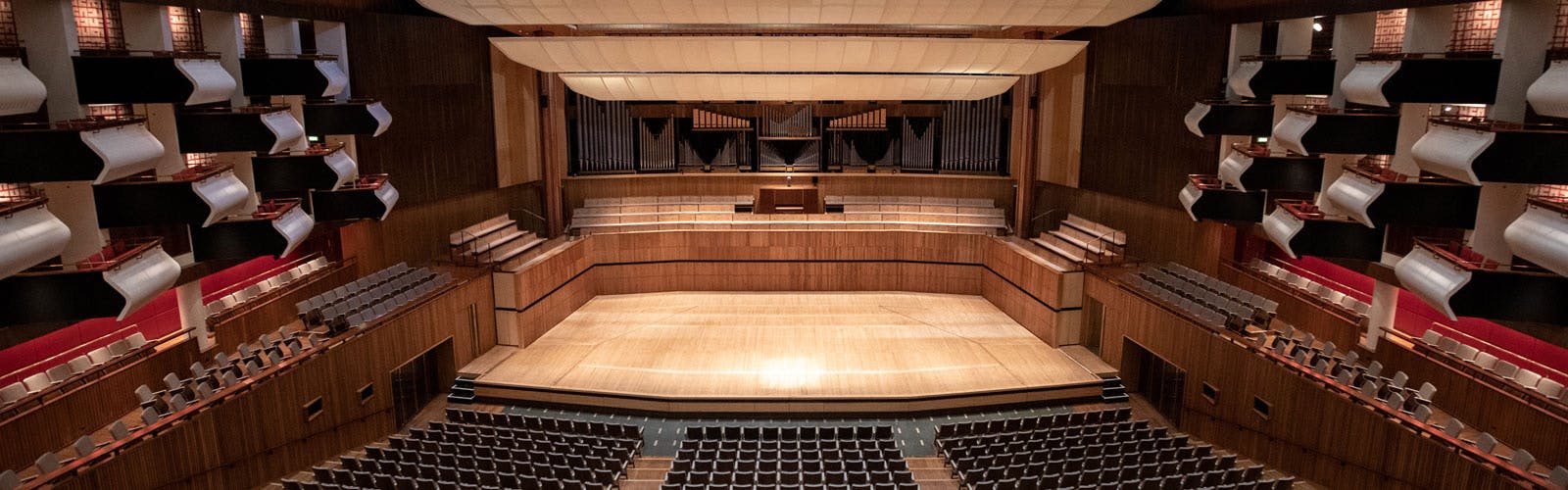 Spacious auditorium with polished wooden stage, ideal for conferences and concerts.