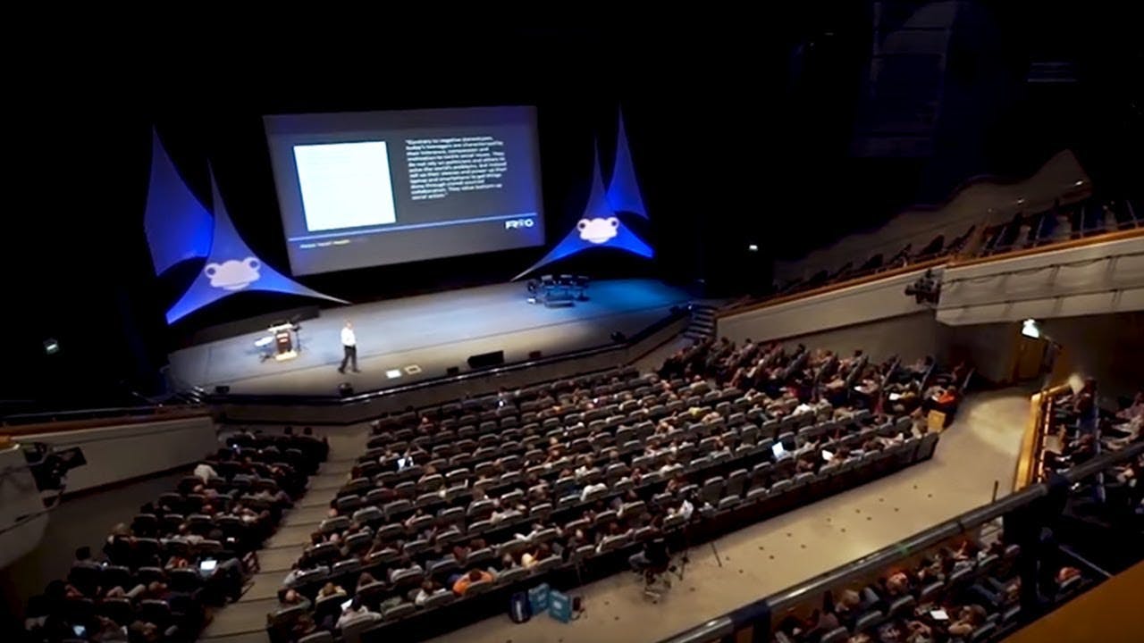 Conference in Hall 11a, ICC Birmingham with speaker and large presentation screen.