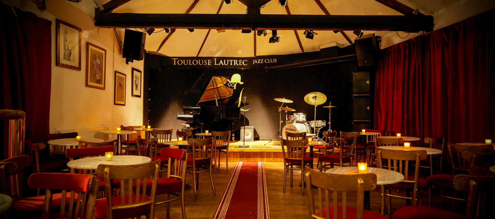 Intimate jazz club in Toulouse Lautrec with warm lighting, perfect for live music events. - Banner