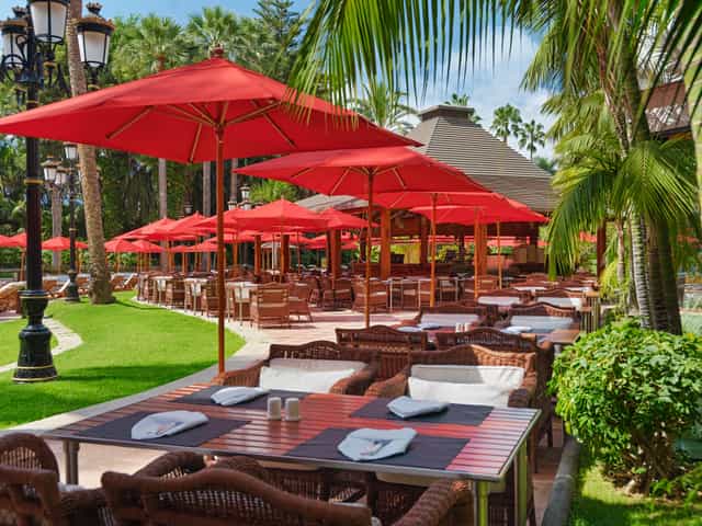 Outdoor dining at The Oriental Restaurant with red umbrellas, ideal for events and meetings.