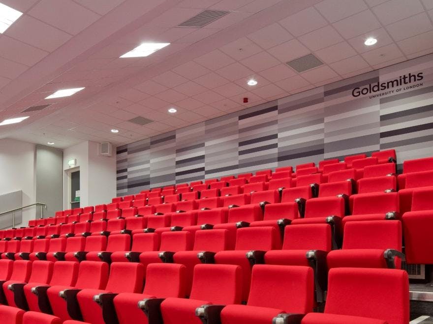 Modern lecture theatre at Goldsmiths, University of London with red tiered seating.