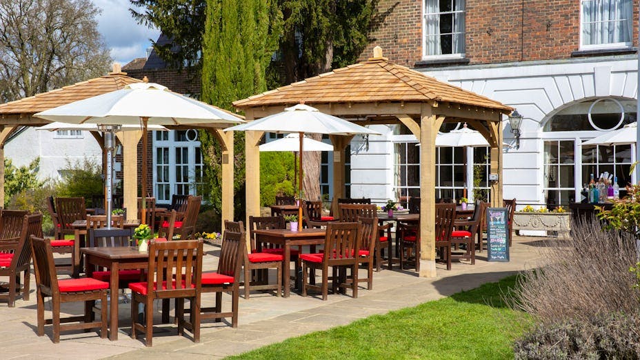 Outdoor event space at West Lodge Park Hotel with wooden gazebos and dining tables.