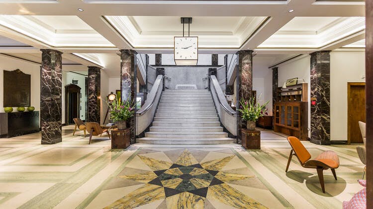 Silk Weaver Bar lobby with elegant marble and staircase, ideal for upscale events.