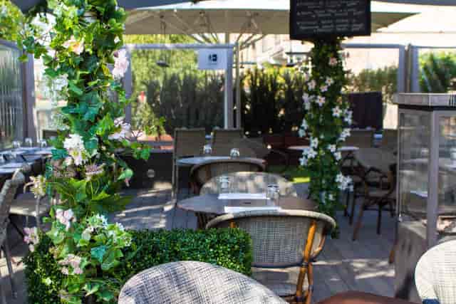 Outdoor terrace dining space with greenery, ideal for casual meetings and events.
