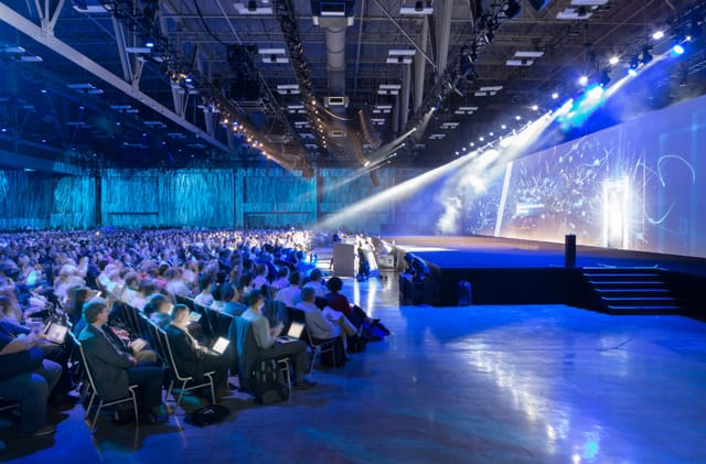 Large conference hall with engaged audience, ideal for professional presentations and events.