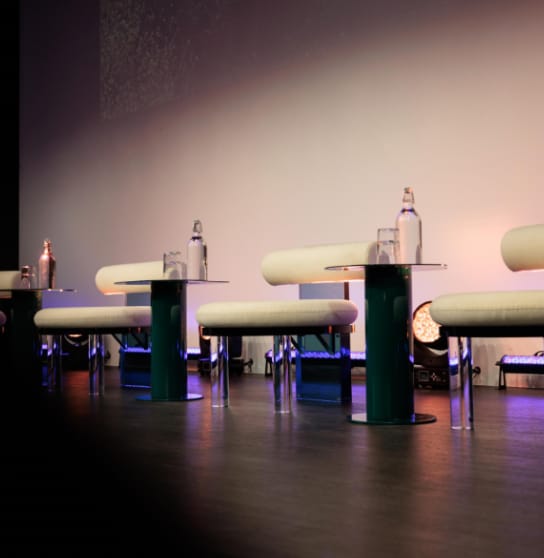 Modern theater stage setup with minimalist seating for panel discussions and presentations.