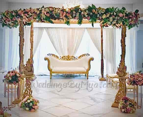 Elegant wedding mandap with floral arch and luxurious sofa for intimate ceremonies.