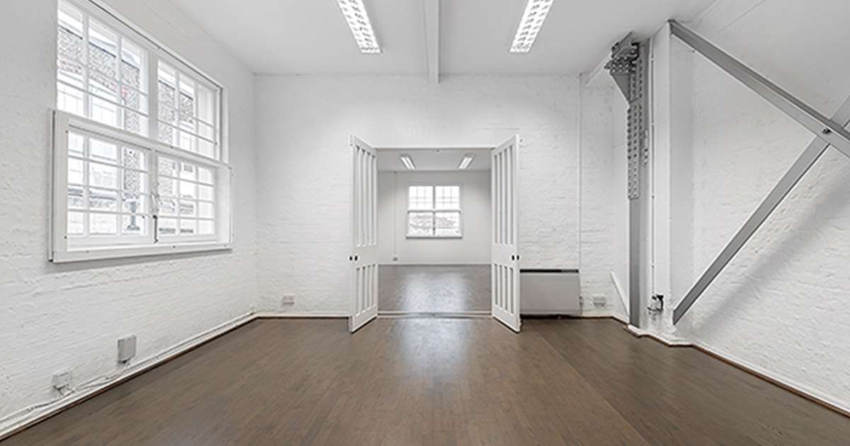 Bright minimalist meeting room with natural light, ideal for workshops and gatherings. - Banner