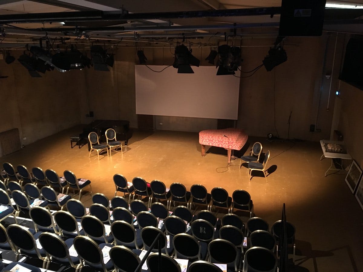 Intimate event space at The Playground Theatre with stage and piano setup.