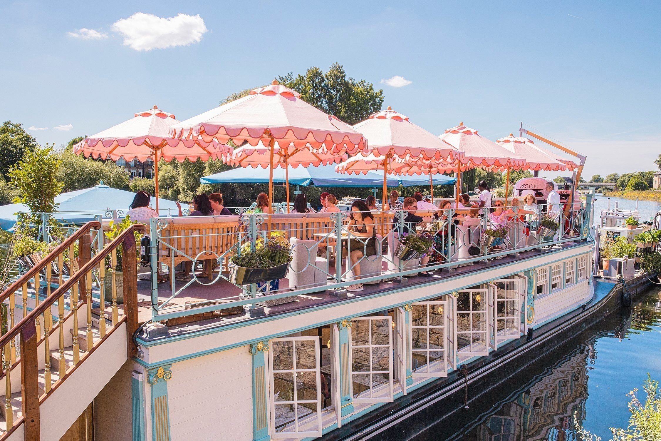 Vibrant outdoor restaurant on a boat with colorful umbrellas for unique events. - Banner