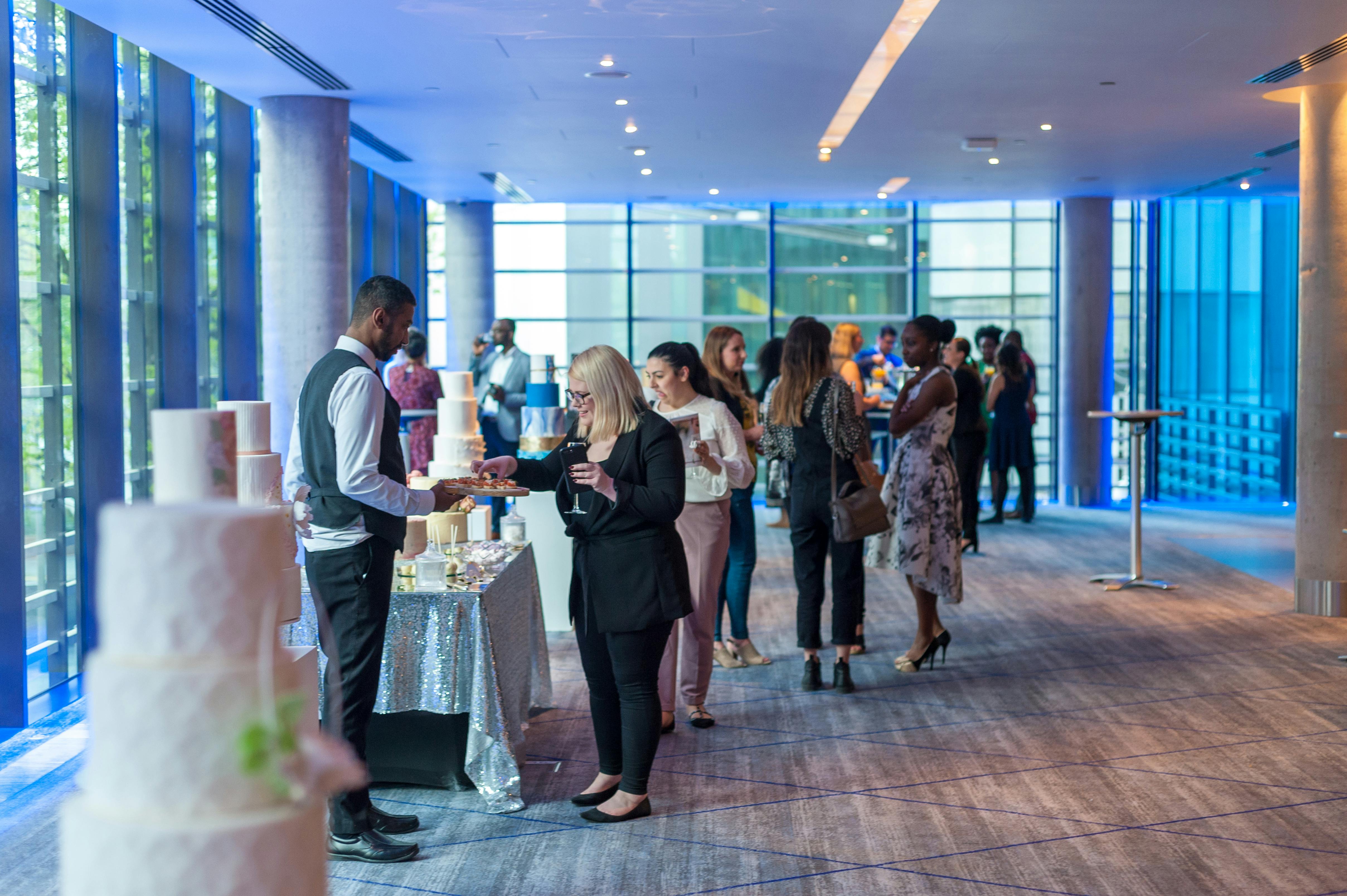 Tower Foyer at Hilton London Tower Bridge, vibrant cake tasting event with attendees.