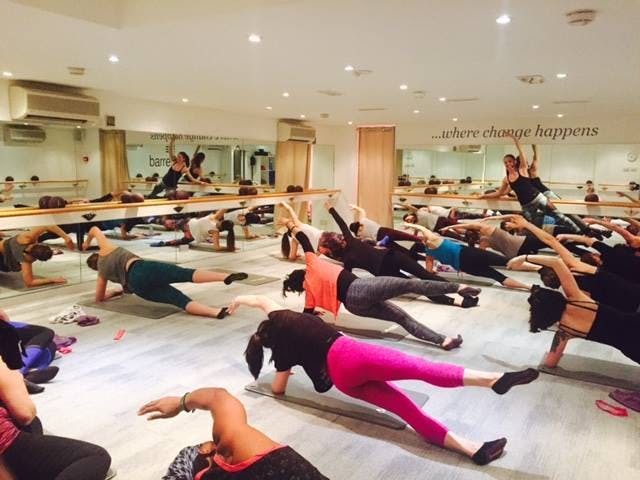 Dynamic group fitness class in bright Barrecore Wimbledon studio for wellness retreats.