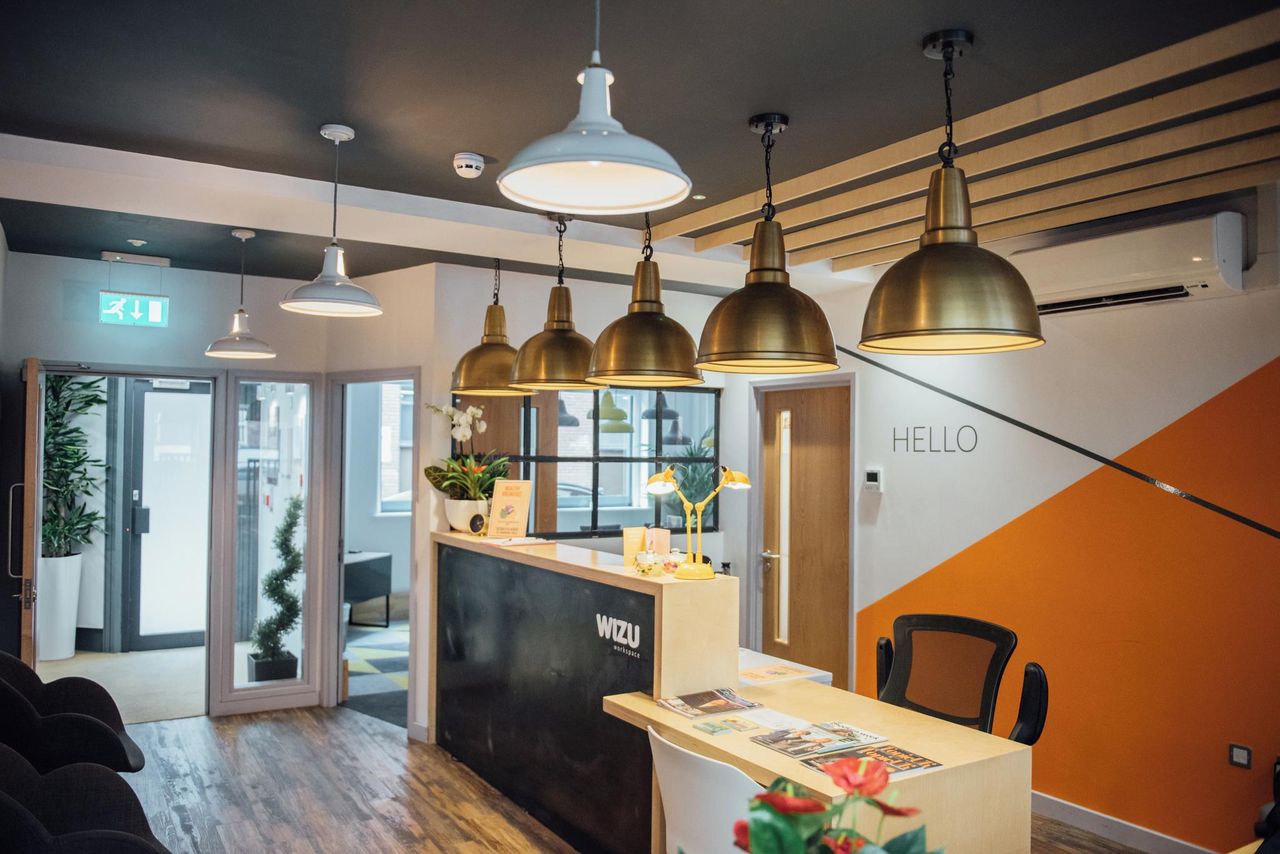 Modern reception area with warm lighting in Wizu Workspace for meetings and events. - Banner