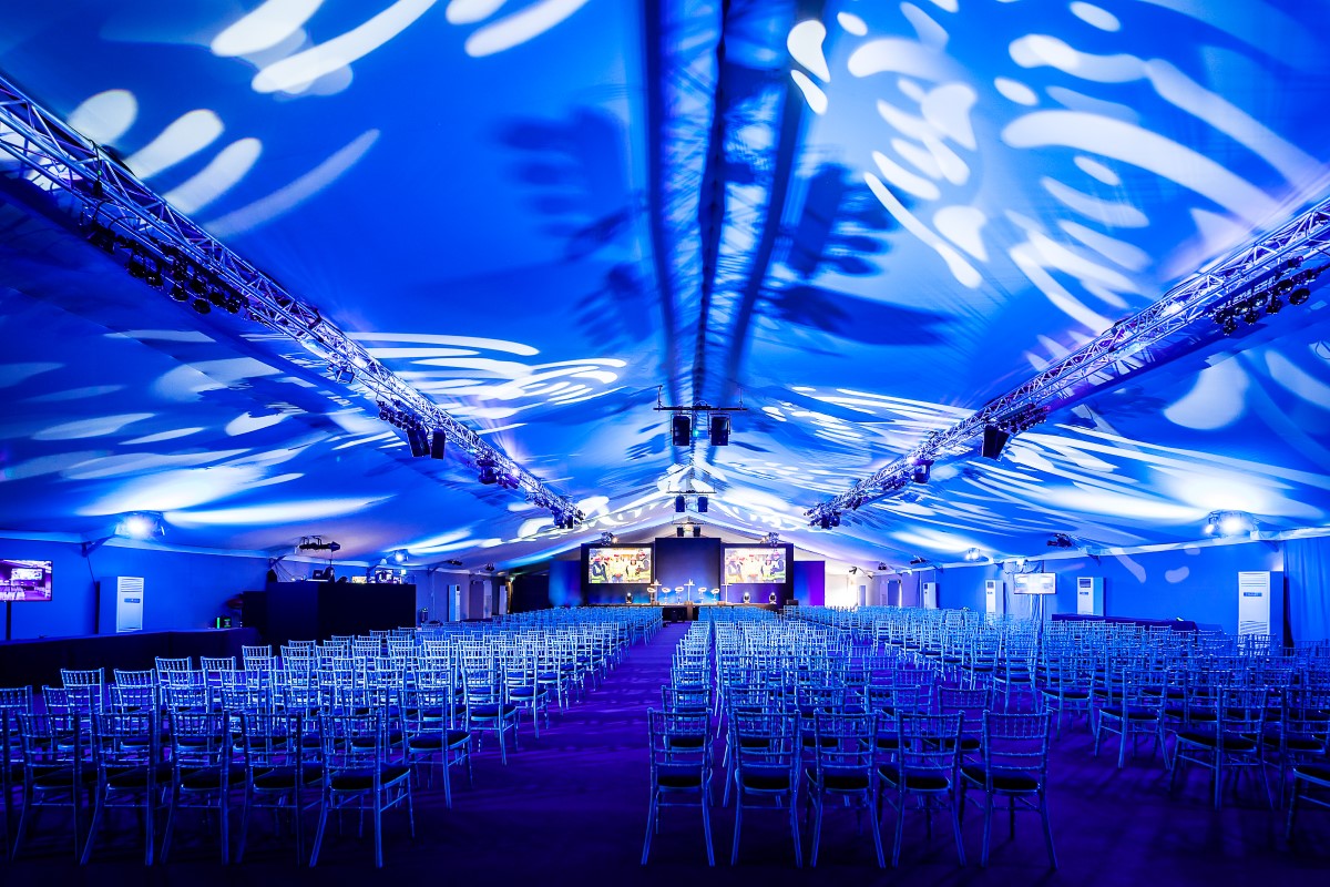 Spacious event tent with blue lighting, ready for a conference or presentation. - Banner