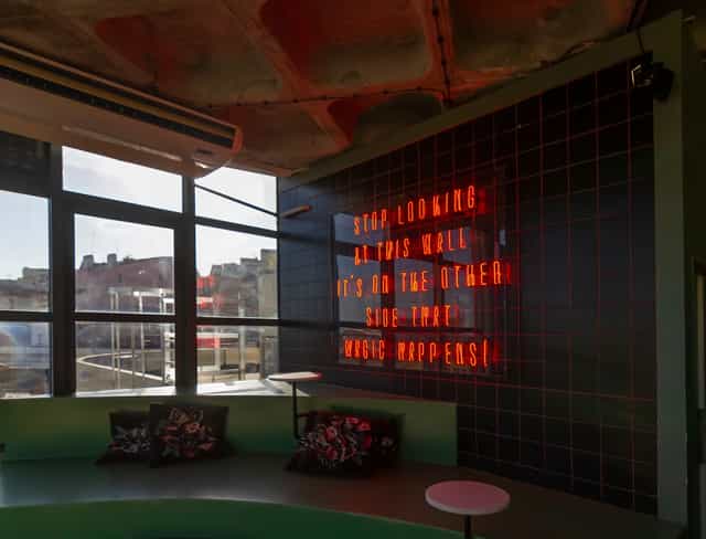 Rooftop meeting space in TOPO Lisboa with neon sign for creative workshops.