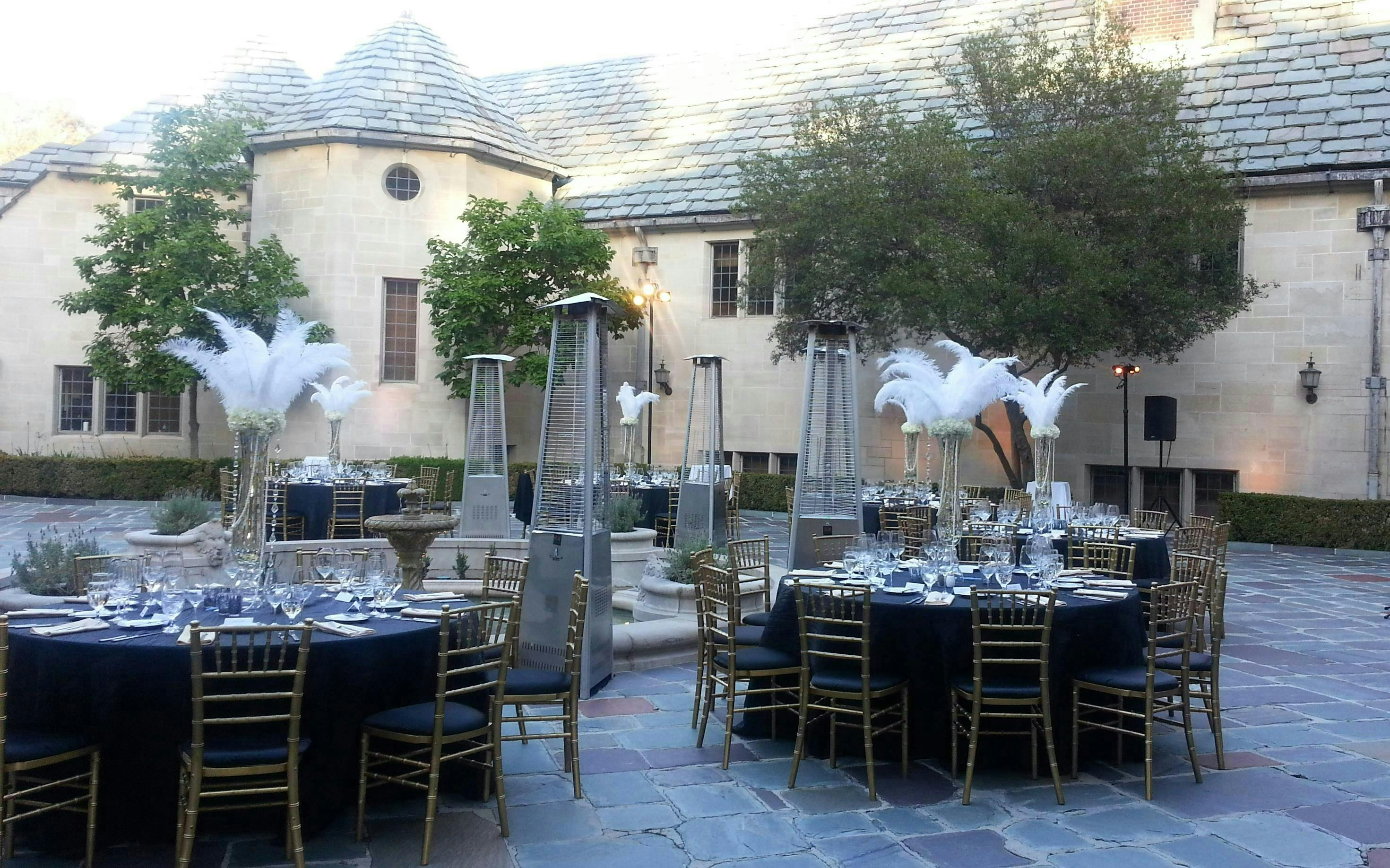 Elegant outdoor event setup at Greystone Mansion with black tables and gold chairs.