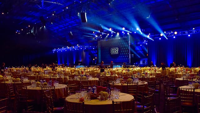 Elegant banquet setup in California's Barker Hangar with gold chairs and blue lighting.