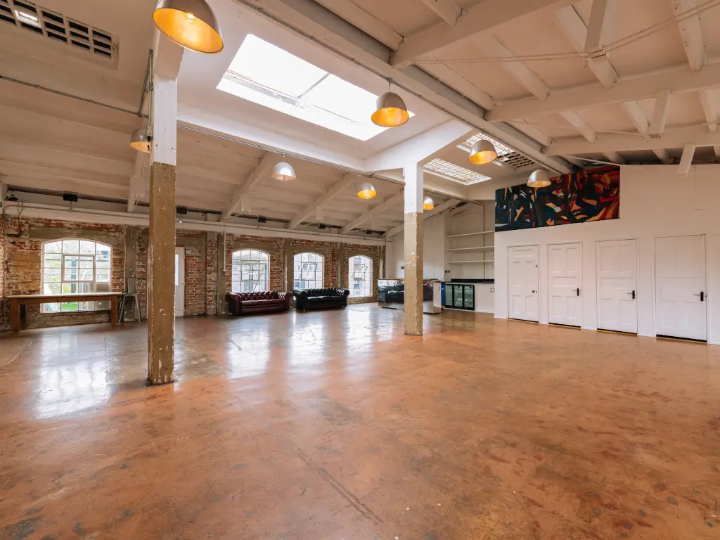 Spacious industrial-chic event space with high ceilings for corporate meetings and workshops. - Banner