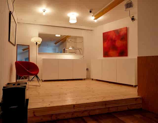 Versatile Second Floor Event Space with wooden flooring and red accent chair for gatherings.