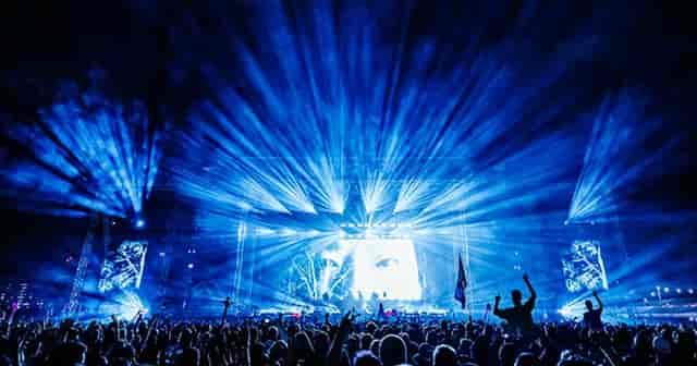 Vibrant concert scene on Silverworks Island with dynamic blue lighting and large screens.