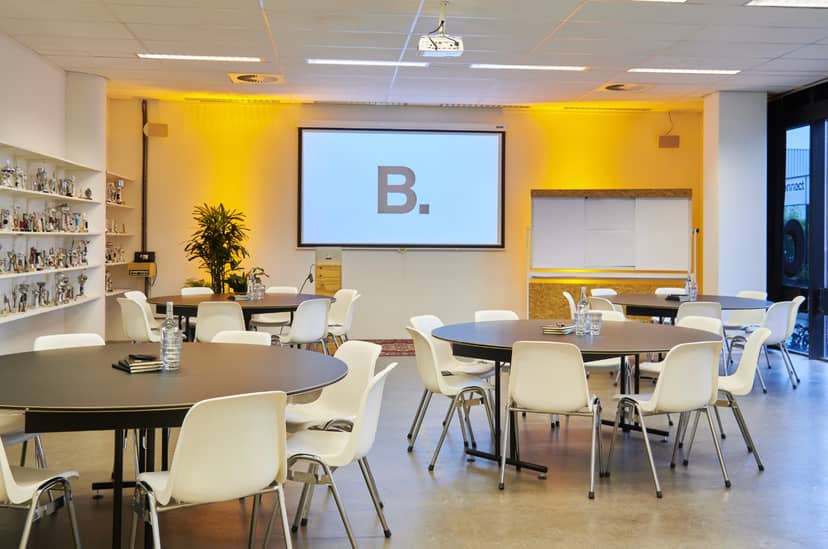 Versatile meeting space with round tables, ideal for workshops and presentations in B. Amsterdam.
