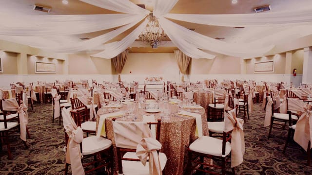 Elegant indoor ballroom with gold tables, perfect for weddings and corporate events.
