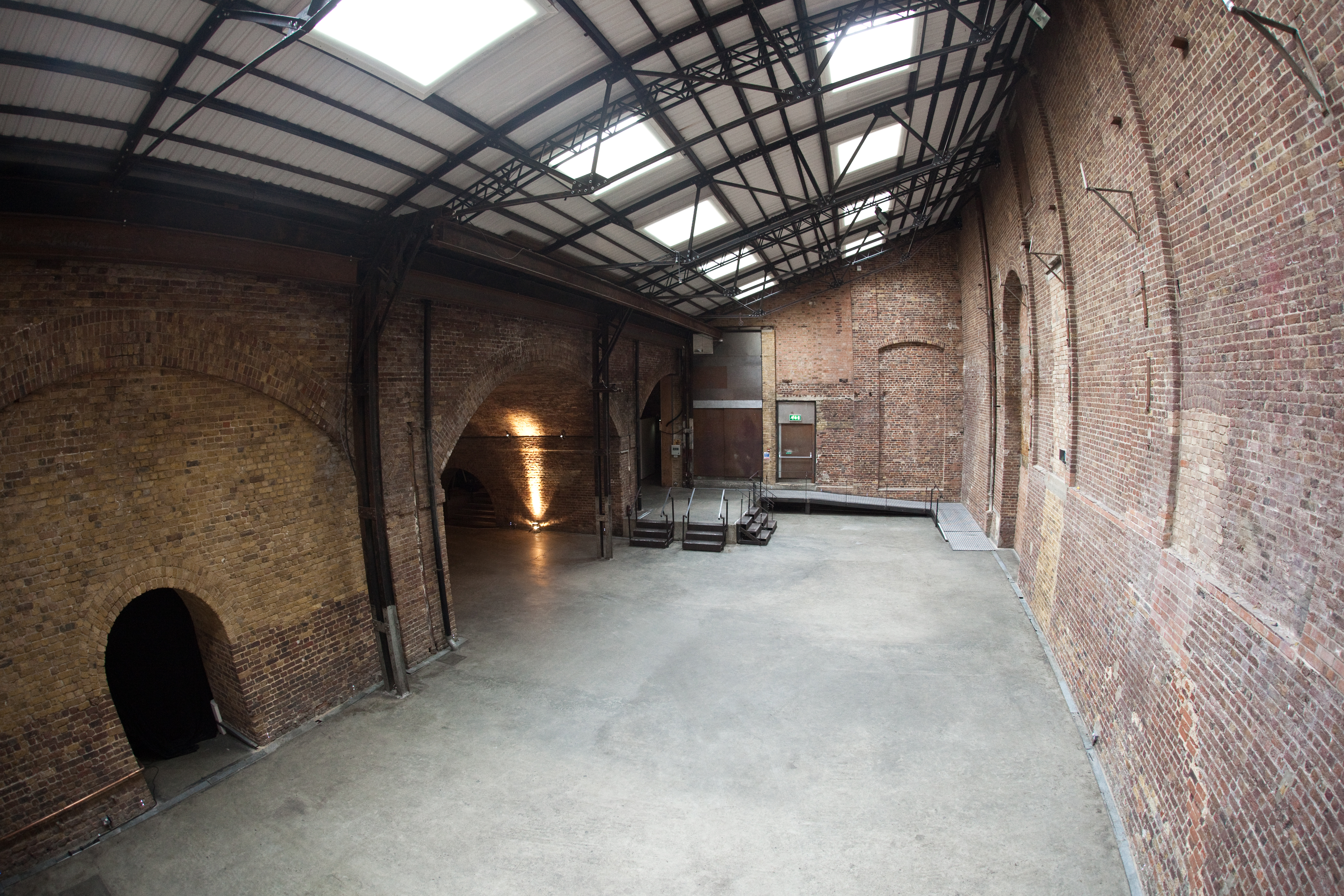 Spacious industrial venue with exposed brick, perfect for creative events and gatherings. - Banner