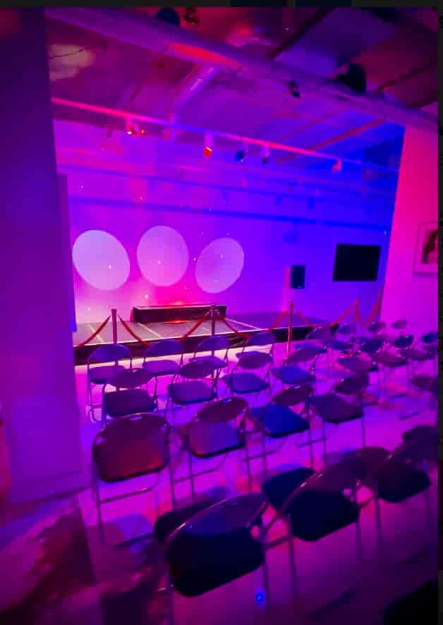 Brunswick Art Gallery event space with stage, vibrant lighting, and elegant seating.