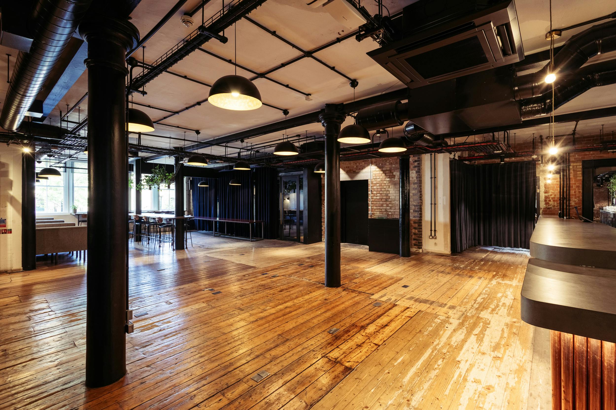 Versatile industrial event space with exposed beams, ideal for corporate meetings and social gatherings.