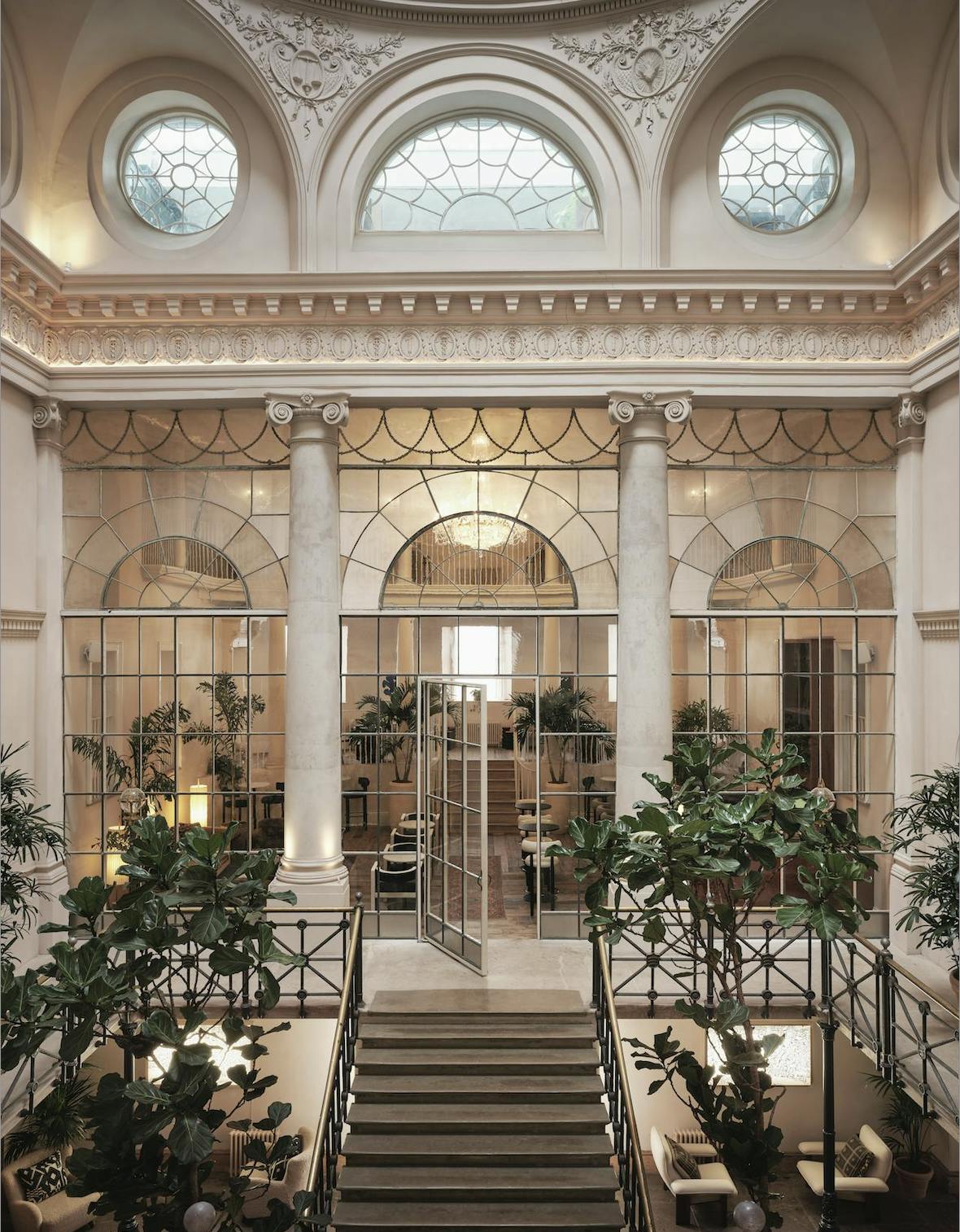 Elegant event space with tall columns and greenery for corporate functions or gatherings.