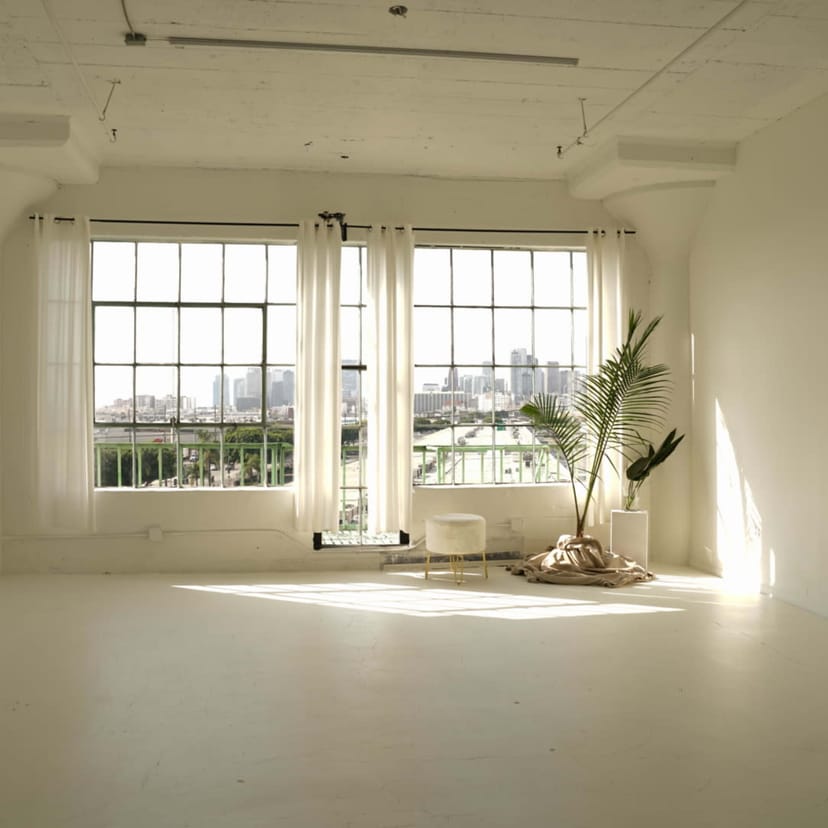 Bright event space in Francisco Studios LA with large windows and city skyline view.