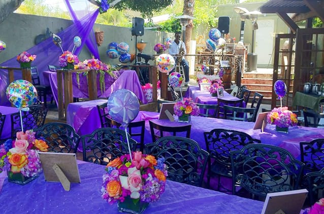 Vibrant event space with purple tablecloths and floral centerpieces for celebrations.