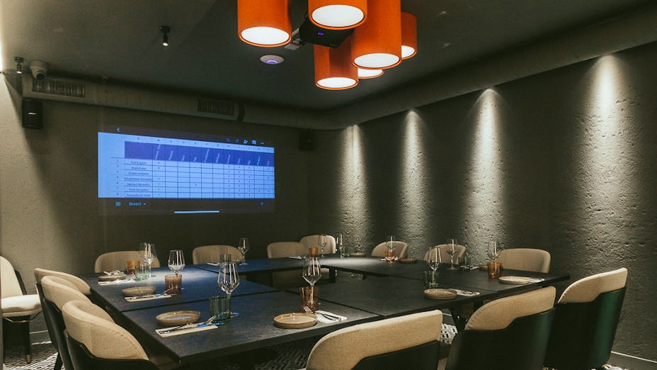 Private meeting room with projector at Bennie Restaurant & Bar for professional events. - Banner