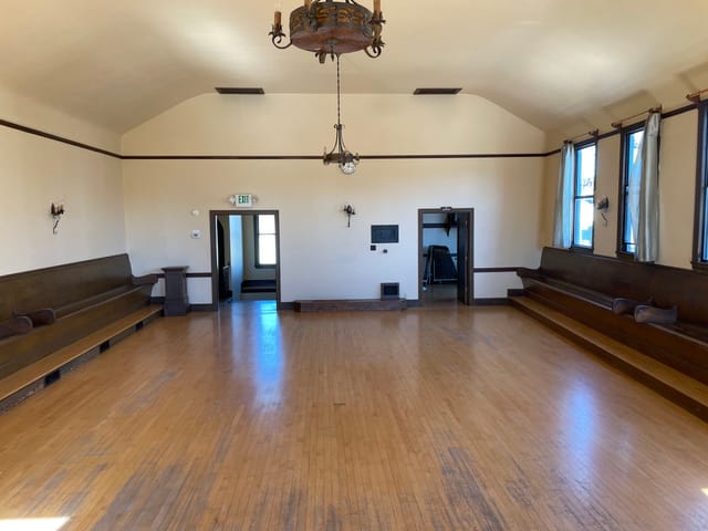 Spacious meeting room with wooden benches, ideal for workshops and social events.