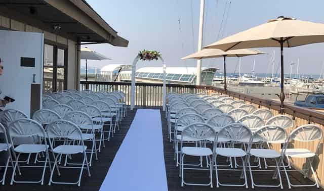 Outdoor wedding venue at Dominic's, featuring white chairs and floral arch by marina.