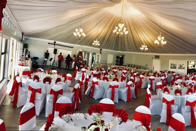 Elegant event space with draped ceilings and red sashes, perfect for weddings and gatherings.