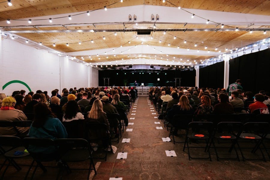 Outdoor event venue with string lights, audience seating, and stage setup for presentations.