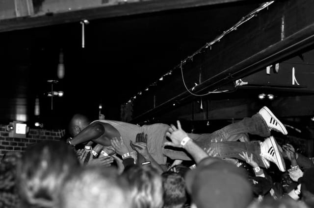 Crowd-surfing performer at a lively outdoor event in The New Parish patio.