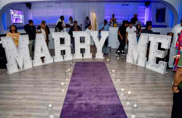 "Staged proposal setup with 'MARRY ME' letters in elegant event space for engagements."