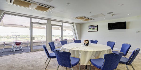 Grandstand Double Box at Sandown Park: bright meeting room with round table and blue chairs.