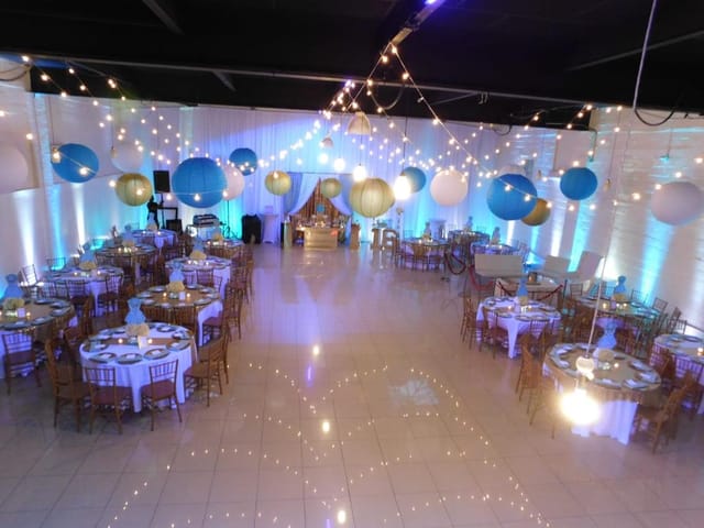 Elegant event venue with round tables, balloons, and soft lighting for weddings or corporate events.