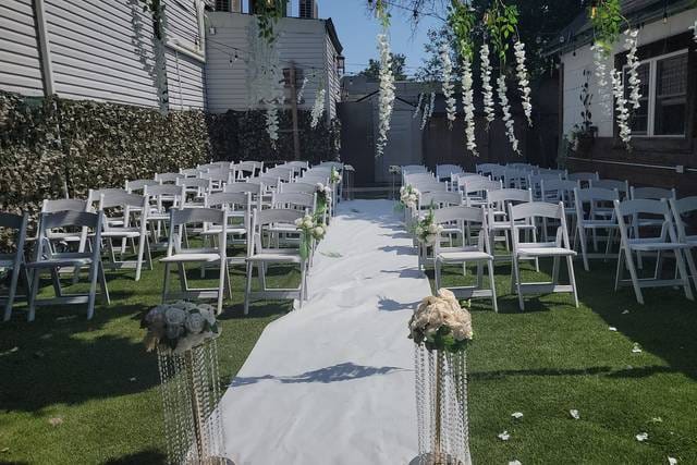 Outdoor wedding ceremony setup with floral aisle and white chairs at R Studio Events.