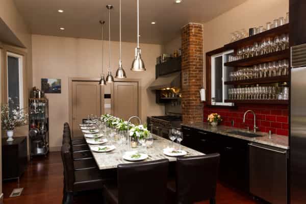 Stylish outdoor kitchen with elegant dining setup for gourmet events and private dinners.