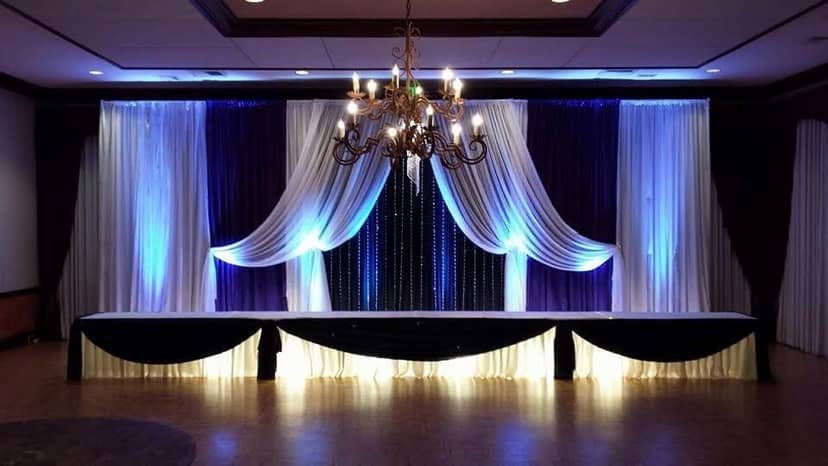 Elegant stage setup with purple and white drapes for weddings and corporate events.