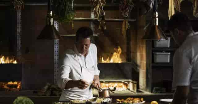 Chef preparing dishes in rustic kitchen for immersive dining events and cooking classes.