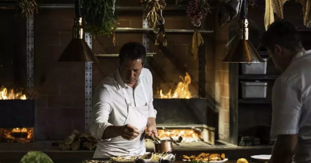 Chef preparing dishes in rustic kitchen for immersive dining events and cooking classes.