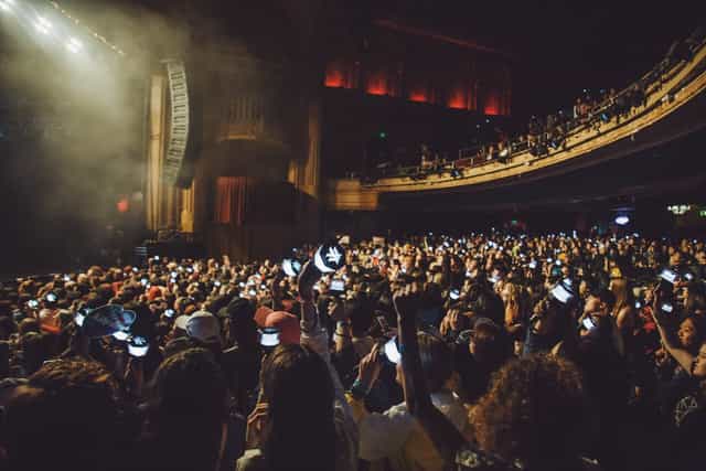 Vibrant crowd at The Warfield concert, illuminated by smartphones, showcasing audience engagement.